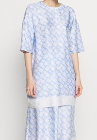 Vestito azzurro chiaro con un motivo floreale, maniche corte, scollatura rotonda e una texture liscia simile alla seta.