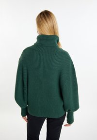 Pulover verde din tricot cu nervuri, cu guler înalt, croială lejeră și umeri căzuți. Textură moale, mâneci lungi și fante pe laterale la tiv.