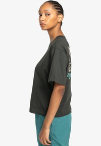 Dark green cotton t-shirt with short sleeves, loose fit, featuring a graphic design in light colors on the back.