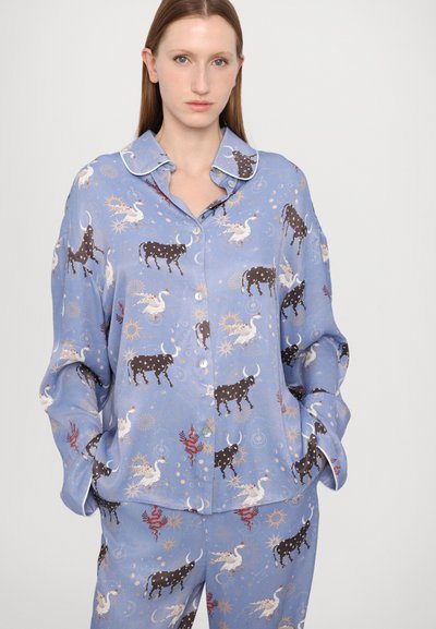 Set de pijamale de culoare albastru deschis, cu un model fantezist de vaci negre și creaturi mitologice, având cămașă cu guler și închidere cu butoni.