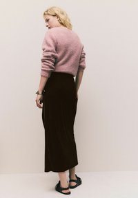 Hellrosa, flauschiger Pullover mit langen Ärmeln, kombiniert mit einem dunkelbraunen, knöchellangen Rock und schwarzen Sandalen. Einfaches, strukturiertes Design.