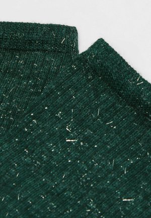Groene gebreide stof met glanzende metalen draden die er doorheen zijn geweven, gevouwen aan de randen op een lichte achtergrond.