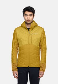 Veste isolée jaune avec une fermeture éclair à l'avant, une capuche et des manches contrastantes couleur sable. Présente un matelassage diagonal et un logo discret.