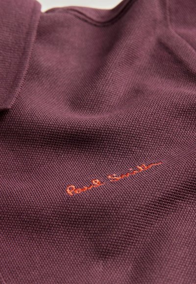 Polo shirt bordeaux realizzato in tessuto testurizzato, con un ricamo arancione della firma "Paul Smith" sul davanti.