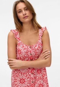 Floral-patterned dress in red and white, featuring a scoop neckline, ruffled straps, and front button closure.
