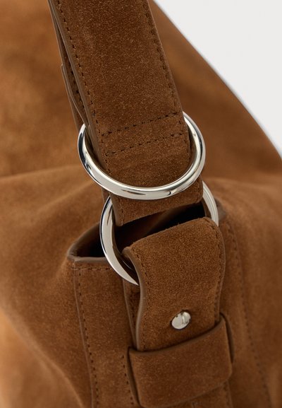 Rudas zomšo rankena su sidabro metaliniu žiedu, lygiu paviršiumi ir siuvinėjimo detale su užsegimu.