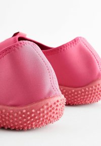 Rosa Wasserschuhe mit einer strukturierten, gepunkteten Sohle, gefertigt aus weichem Stoff. Sie verfügen über ein nahtloses Design und eine flexible, leichte Struktur.
