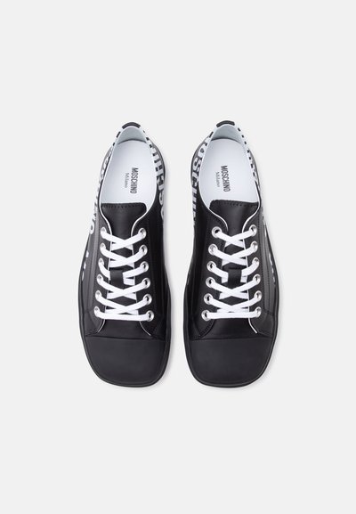 Ζευγάρι μαύρα παπούτσια τύπου low-top με λευκά κορδόνια και λογότυπο "Moschino Milano" στη γλώσσα και τις εσωτερικές σόλες, από πάνω.