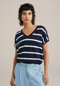 Námořnická a bílá pruhovaná krátkosá v-neck top vyrobený z lehké tkaniny, spárovaný se světle modrými skládacími kalhotami, které mají zapínání na knoflíky.
