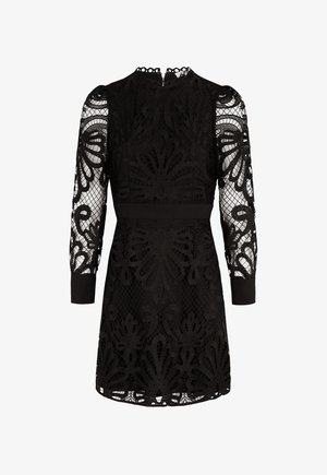 Robe noire avec un voile en dentelle à motifs floraux, manches longues transparentes et poignets unis. Taille ajustée et décolleté rond.