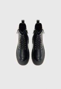 Czarne skórzane botki za kostkę z zaokrąglonym noskiem, sznurowaniem z przodu, srebrnymi elementami i zamkiem błyskawicznym po boku. Posiadają masywną gumową podeszwę i fakturowaną powierzchnię.