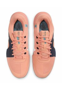 Le sneaker Nike presentano una tomaia in mesh traspirante color pesca, accenti blu navy, suola in gomma testurizzata e dettagli azzurri sulla linguetta.