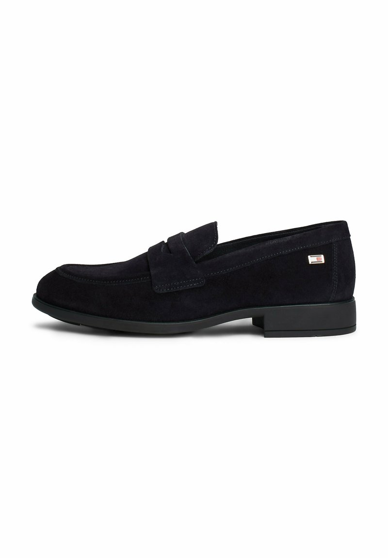 Mocassin homme en daim noir avec petit talon et détail de bride, vue de côté sur fond blanc.