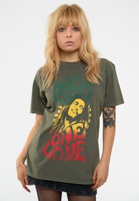 Olive green cotton t-shirt featuring a Bob Marley graphic, with red and yellow text reading "ONE LOVE" and bold patterned accents.