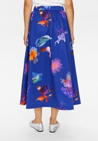 Lange, blaue Blumenkleid mit lebhaften Farben und einer Vielzahl von Blumenmustern. Elastischer Bund mit lockerer Passform. Silberschuhe.