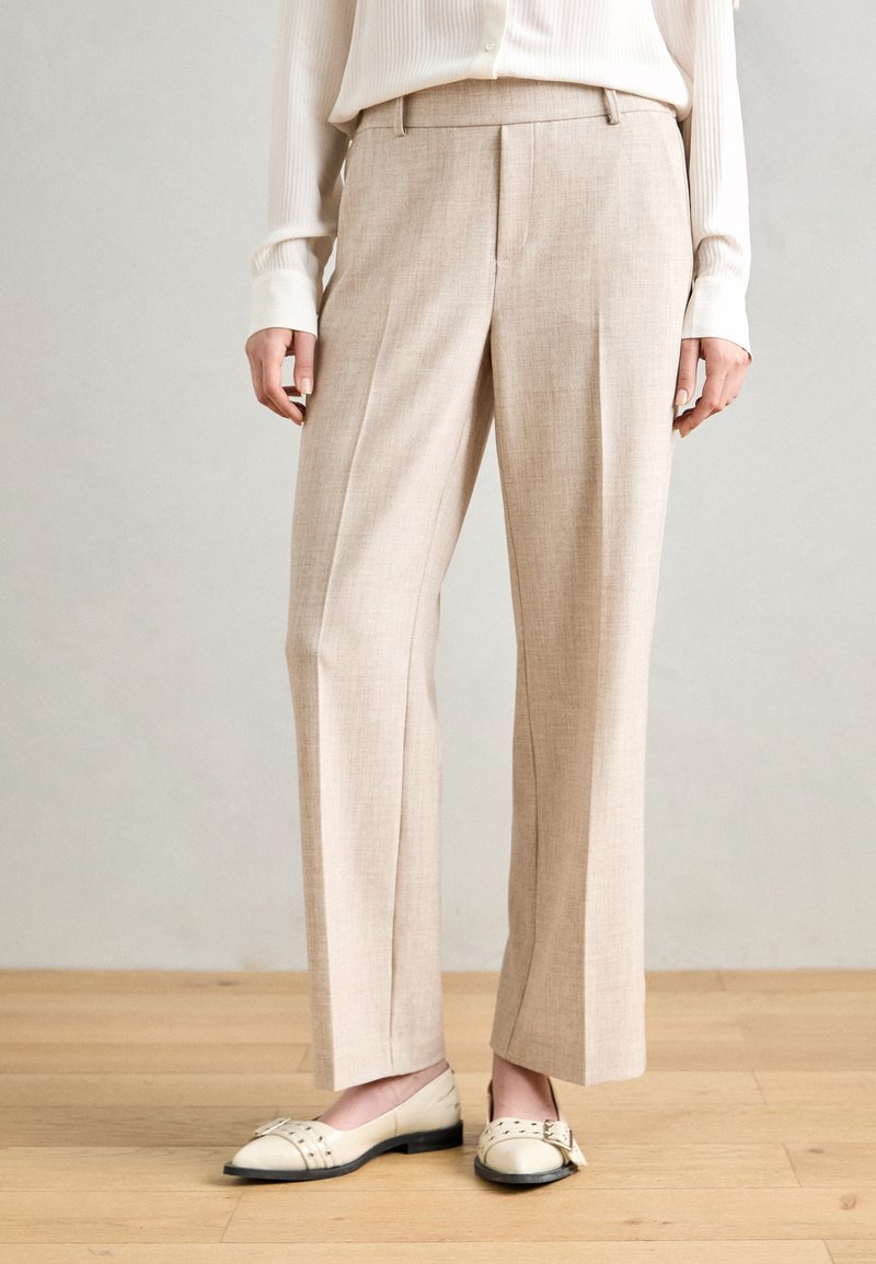 Beige, leichte maßgeschneiderte Hosen mit geradem Schnitt, vorderen Falten und glatter Textur. Kombiniert mit beigen und schwarzen zweifarbigen Ballerinas.