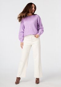 Paarse, gebreide trui met gouden accenten, gecombineerd met hoge witte wijde jeans en bruin luipaardprint enkellaarsjes.