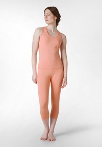 Ferskenfarvet atletisk tanktop og capri leggings, lavet af blødt, strækbart materiale, med en tætsiddende design og en simpel halsudskæring.