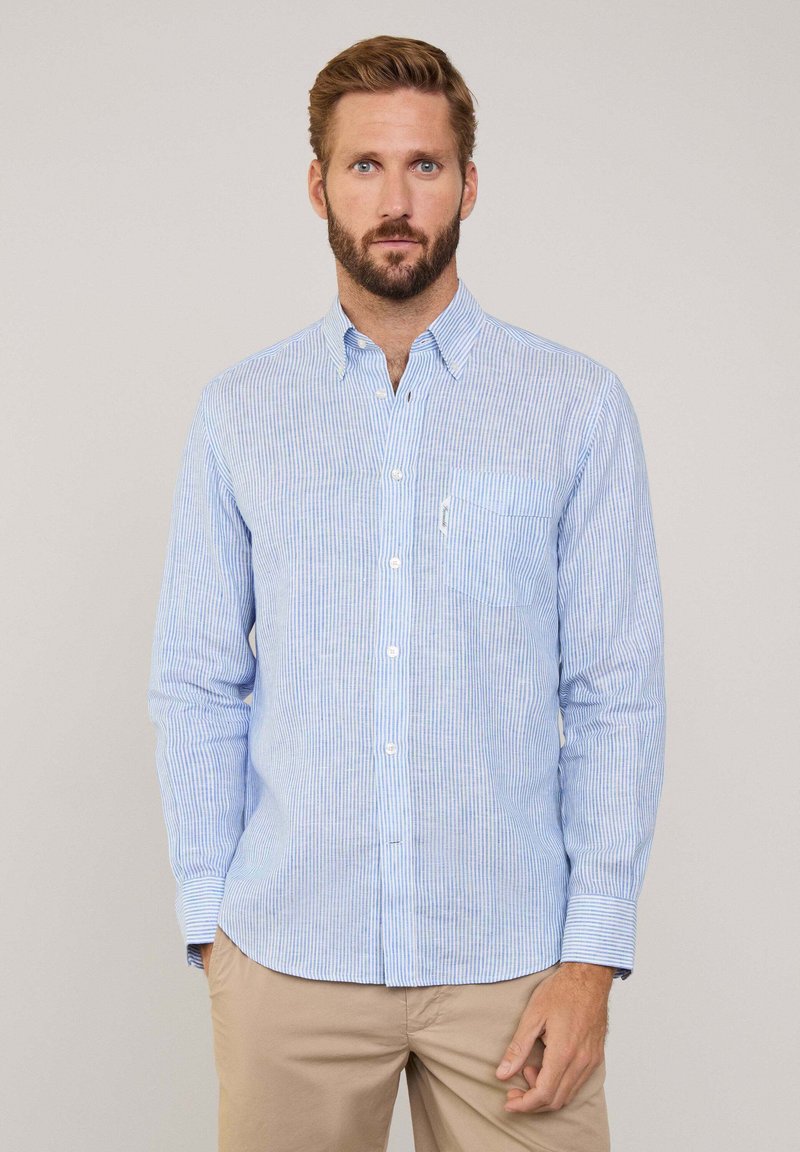 Camicia a righe blu chiaro con bottoni, maniche lunghe e taschino sul petto. Realizzata in tessuto leggero, presenta un colletto classico e maniche ripiegate.