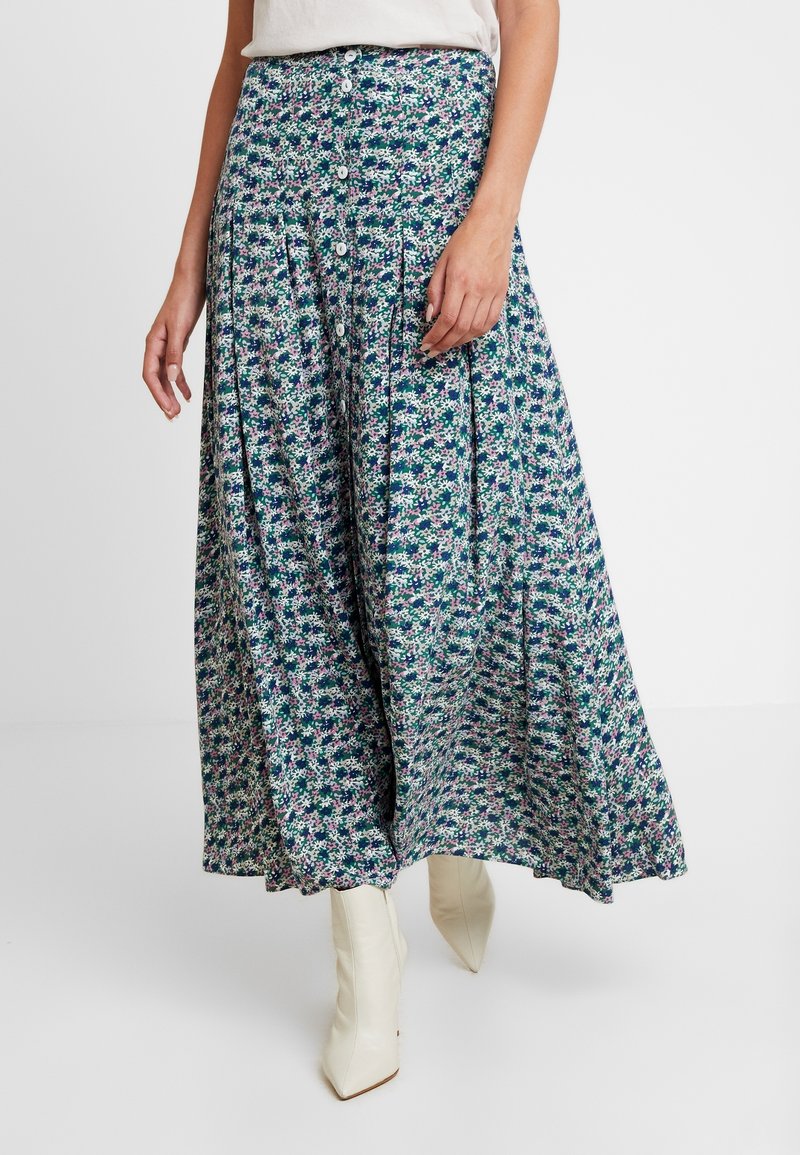 Blumen-Midi-Rock in Grün, Blau und Lila. Mit Knöpfen vorne, Falten und einem weichen, leichten Stoff. Trägt man mit weißen Stiefeln.