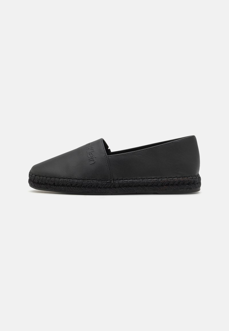Espadrille en cuir noir au design épuré, dotée d'une semelle en jute tissé et sans matériel ou accents visibles. Texture lisse, forme minimaliste.