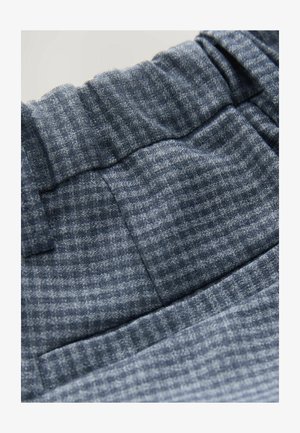 Pelēks austu audumu ar strukturētu rakstu, kas satur elastīgu jostu un smalkus pārbaudījumus dažādās pelēkās toņos.