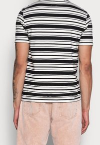 T-shirt a maniche corte a righe in bianco e nero, realizzato in tessuto morbido, con scollatura a girocollo e silhouette aderente.