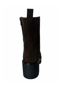 Botín de ante marrón con un tacón negro estriado. Cuenta con un cierre de cremallera y una tira en la parte trasera. Textura suave en general.