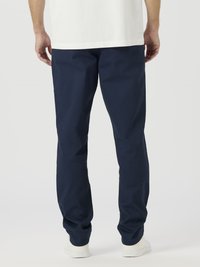 Pantalones de algodón azul marino con corte recto, que cuentan con bolsillos laterales y una textura suave. Combinados con una camisa blanca y zapatos de color claro.