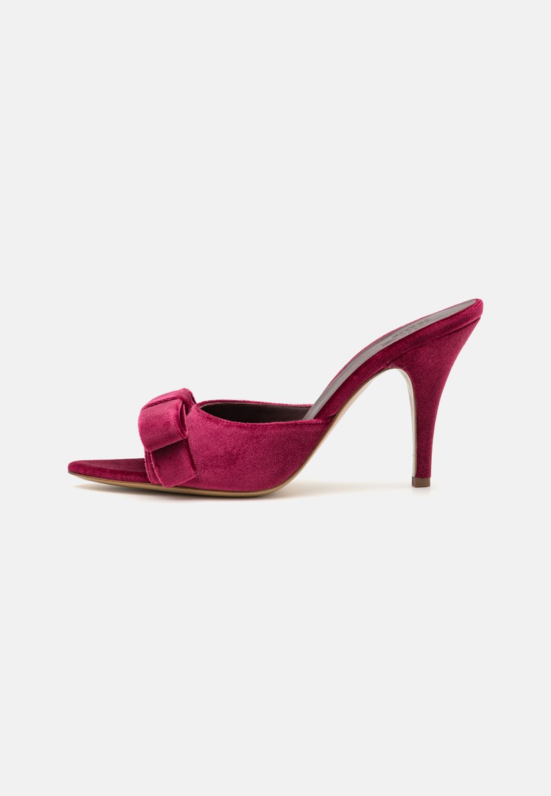 Sandal s visokom potpeticom od baršuna u tamno ružičastoj boji s naglaskom na mašnu i otvorenim prstima, s elegantnom stiletto potpeticom i glatkom teksturom.