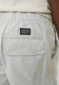 Lys grå bomuldsshorts med elastisk talje, der har en baglomme og et mærket label, der viser en glat tekstur og en afslappet stil.