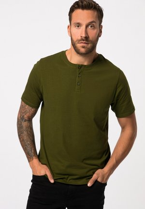 Camiseta de manga corta verde oliva hecha de tela suave, con cuello redondo y tapeta de tres botones, combinada con pantalones negros.