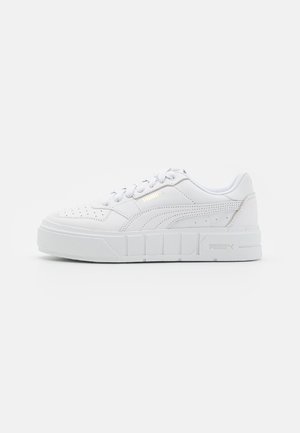 White low-top sneakers with perforated detailing, a textured rubber sole, and subtle gold accents on the side logo. Smooth synthetic material.
