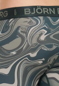 Κολάν εφαρμοσμένα με μαρμάρινο σχέδιο σε αποχρώσεις γκρι και πράσινου του βελούδου. Διαθέτει μαλακή ζώνη στην καφέ με χρώμα σκούρο πράσινο και λογότυπο «BJÖRN BORG». 