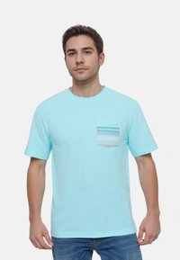 Camiseta de rayas azul claro en tejido suave con un bolsillo en el pecho que presenta rayas horizontales en azul y blanco. Manga corta, escote redondo.