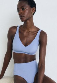 Lys blå, sømløs bralette og høyhåndsdelt bikini laget av glatt stoff; har en dyp V-hals og brede stropper for komfort.