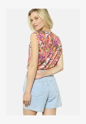 Halter top s kvetinovým vzorom s jasnými ružovými, oranžovými a zelenými motívmi, skombinovaný s svetlomodrými denimovými šortkami so zadnými vreckami.