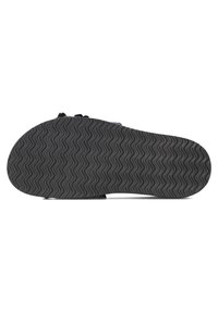 Zwarte rubberen sandaalonderzijde met een gestructureerd zigzagpatroon voor grip. Kenmerkt zich door een gladde, gebogen vorm met verhoogde randen.