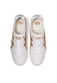 Sneakers bianchi con dettagli in pelle marrone, dotati di punta arrotondata, lacci piatti e logo sulla linguetta. Texture liscia, design classico.