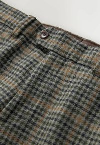 Karierte Wollhose mit grünen, braunen und schwarzen Farbtönen. Ausgestattet mit einem Knopfverschluss und einem weichen, strukturierten Stoff.