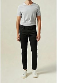 Jean noir à coupe slim, associé à un t-shirt gris clair à col rond. Des baskets blanches complètent la tenue. Design simple, détails minimaux.