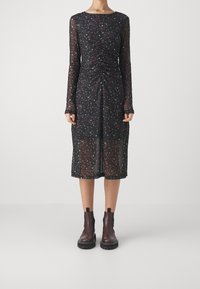 Musta pitkähihaisen mekko, jossa on värikäs kukkakuosi, rypytetty etupaneeli ja läpikuultava kangas. Yhdistetty ruskeisiin nilkkasaappaisiin, joissa on elastiset sivut.