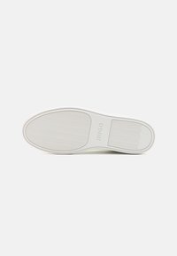 Semelle blanche en caoutchouc avec motif ondulé et le nom de la marque "HUGO" embossé au centre.