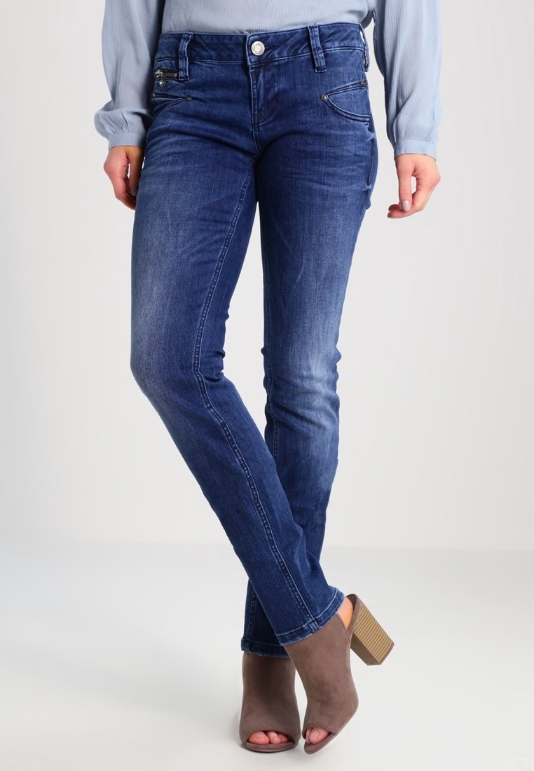 Jins denim biru tua dengan desain pas, dilengkapi saku depan dan sedikit pudar. Dipadukan dengan sepatu hak tinggi abu-abu.