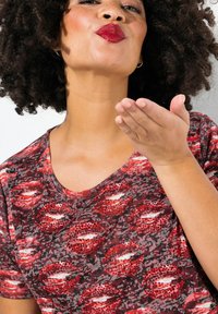 Camiseta gráfica roja y gris con diseño de estampado de labios y acentos de rhinestones, de manga corta y cuello redondo.
