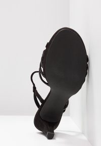 Czarne zamszowe szpilki z paskowym wzorem, szpiczastym noskiem i zwężoną piętą. Podeszwa ma teksturowany wzór antypoślizgowy. Rozmiar oznaczony jako 37.