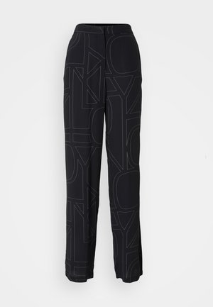 Black pants featuring a textured design of large letters in a contrasting color, with a relaxed fit and wide legs. Elastic waistband visible.