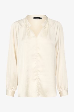 Bluzica v kremni barvi, izdelana iz lahkotnega in strukturiranega materiala. Ima V-izrez, dolge rokave z elastičnimi manšeti in sprednje gumbne detajle.