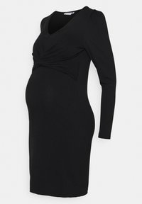 Robe de maternité noire à manches longues, longueur genou, col en V et détail froncé sous la poitrine, silhouette ajustée.