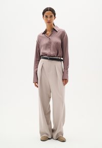 Siden, mauve skjorta med knappar och långa ärmar; högmidjade, vida beige byxor; svart bälte; mjuk textur; minimalistisk design.